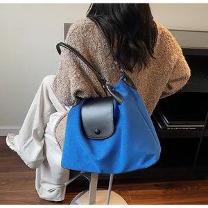Detail of royal blue suede tote bag with black leather straps and magnetic closure