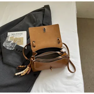 Detailed interior of brown PU leather shoulder bag showing compartments and wood bead tassel