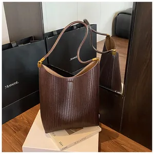 Détail du sac à bandoulière en cuir tressé marron foncé avec boucles dorées