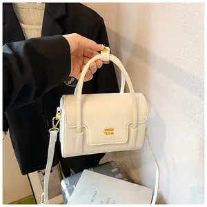 Detail of minimalist beige PU leather bag with gold logo and adjustable shoulder strap