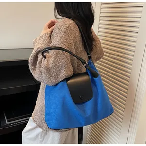 Detail of Klein blue suede tote bag with black leather flap and cylindrical strap