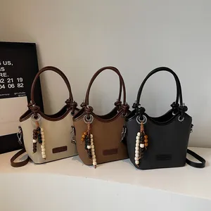 Trois sacs seaux en beige, marron et noir avec texture lychee et gland en perles de bois