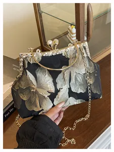 Détail de broderie florale vintage sur sac noir avec fermoir perle dorée et anses métal