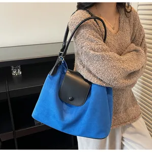 Deep blue oversized tote bag with black leather straps shown on a model