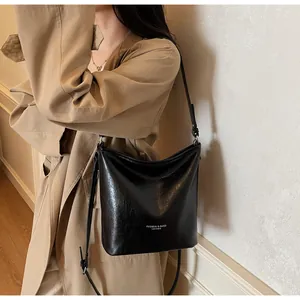 Détail du sac cabas en cuir noir brillant avec finition texturée et lettrage blanc mode