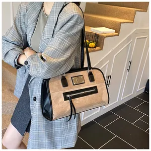 Détail d'un sac cabas chic en daim beige avec accents en cuir noir et pompons à franges