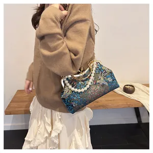 Detail of vintage blue handbag with phoenix embroidery and large pearl handle