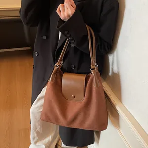 Detail of vintage brown suede tote bag with smooth leather trim and metal buckle closure