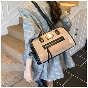 Détail du sac cabas en daim kaki avec garniture en cuir noir et accent doré sur modèle