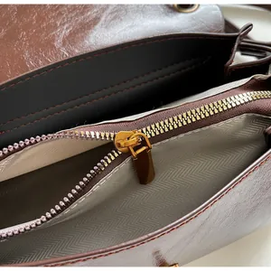 Detail view of the brown leather handbag interior featuring a bronze zip pocket and lining