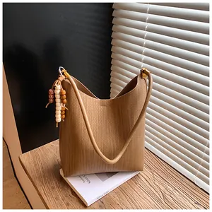 Gros plan d'un sac cabas tissé kaki avec pampilles en perles de bois et texture
