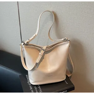 Détail du sac seau en cuir blanc crème montrant le logo de mode et les ferrures argentées