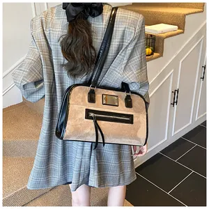 Détail d'un grand sac cabas rétro en daim marron avec bandoulière noire sur un blazer
