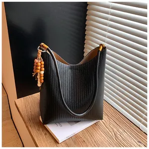 Gros plan sur un cabas noir en cuir tressé avec boucle dorée et pendentif à pampilles