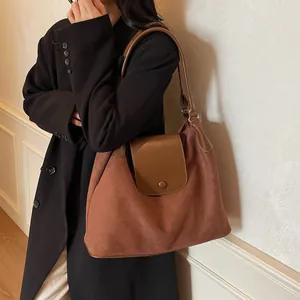 Detail of brick red suede tote bag with brown leather contrast and elegant button closure