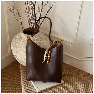 Gros plan sur le cuir marron foncé à texture tressée et la boucle en métal doré