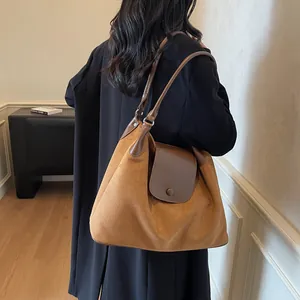 Side view of caramel brown suede tote bag with flap closure on black coat model