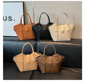 Sacs seaux multicolores en cuir grainé disposés sur un canapé noir pour le bureau
