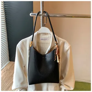 Détail d'un sac hobo en cuir tressé noir avec des breloques décoratives en perles vintage