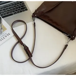 Détail d'un sac cabas en cuir ciré marron foncé avec boucles argentées et bandoulière
