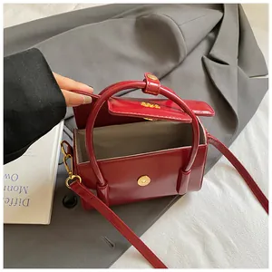 Detail view of red glossy leather bag with magnetic flap and beige fabric lining