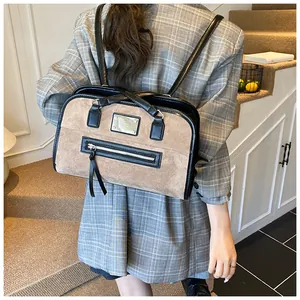 Détail de dos d'un sac cabas en daim beige avec bordure en cuir noir porté par un modèle
