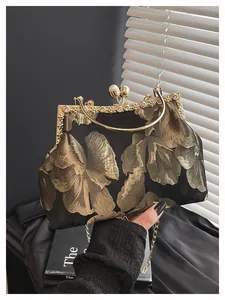 Gros plan du tissu jacquard floral doré et du fermoir perle sur sac de soirée vintage