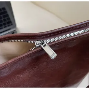 Vue macro de la texture cuir vintage marron et détail du zip argenté sur le sac fourre-tout