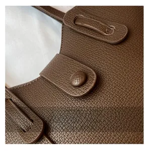 Gros plan sur la texture du cuir marron foncé et la boucle métallique du sac à main