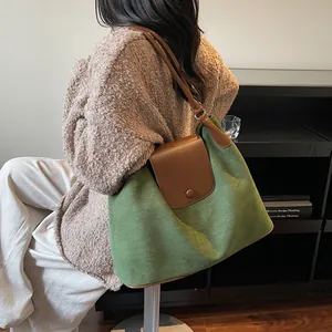 Close-up of large green suede tote bag with brown leather straps for lifestyle wear