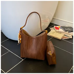 Détail d'un sac cabas tissé marron caramel avec pompon et pochette intérieure