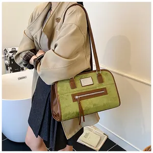 Détail du sac cabas en daim vert avocat avec finitions en cuir marron et plaque métal