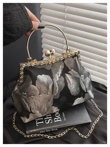 Gros plan sur la broderie florale et le fermoir perle du sac vintage à cadre doré