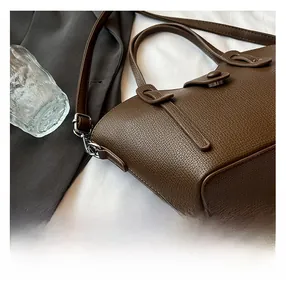 Gros plan détaillé d'un sac à main en cuir marron foncé avec grain de litchi et crochet