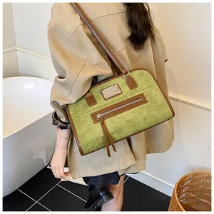 Détail du sac cabas en daim vert avec finitions en cuir marron et poche zippée à pompon