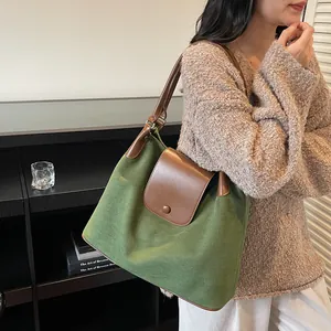 Close-up of forest green canvas hobo bag with dark brown leather trim and metal snap