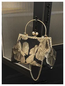 Détails d'un sac de soirée brodé avec motifs floraux dorés et fermoir en perles