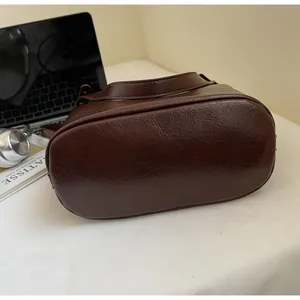 Gros plan du fond ovale et des coutures détaillées d'un sac cabas vintage marron foncé