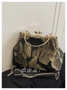 Détail de broderies florales dorées, fermoir perle et cristaux sur pochette de soirée