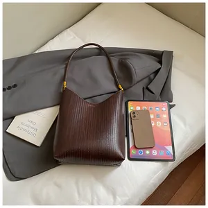Détail du sac hobo tressé marron foncé avec ferrures dorées et mise en scène élégante