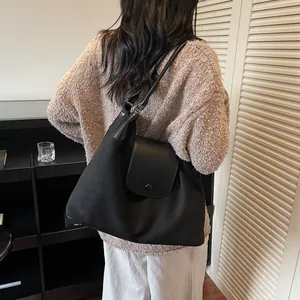 Detail of a black canvas and leather tote bag shown on a model in a cozy interior setting