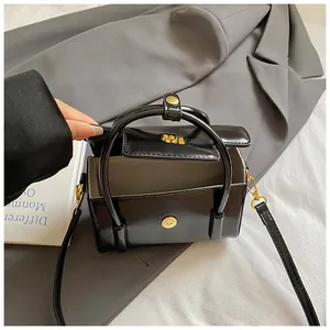 Detail of black glossy PU leather handbag with gold magnetic closure and arc handle