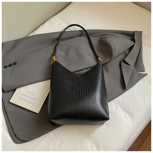 Détail d'un sac cabas en cuir tressé noir avec des boucles en métal doré élégantes