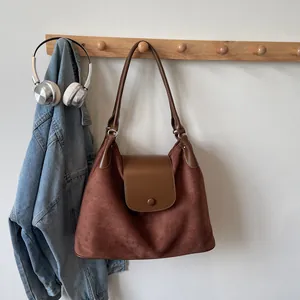 Brown matte suede tote bag with leather flap and strap in a vintage lifestyle setting