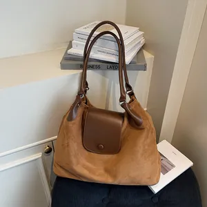 Brown suede tote bag with leather trim, featuring a vintage crescent shape and chain strap