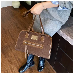 Détail du sac rétro en daim marron avec une plaque métallique dorée décorative élégante