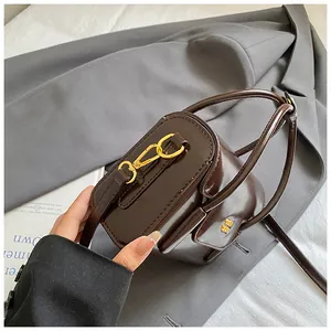 Detail of dark brown glossy patent leather handbag with gold metal lock and fine stitching