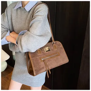 Détail du sac cabas vintage en daim marron avec plaque en métal et long gland sur la fermeture