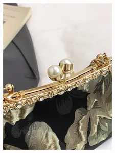 Détail d'une pochette de soirée avec broderie florale dorée et fermoir perle