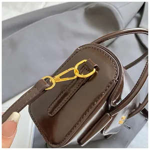 Detail view of glossy brown handbag with premium gold metal clasp and stitching